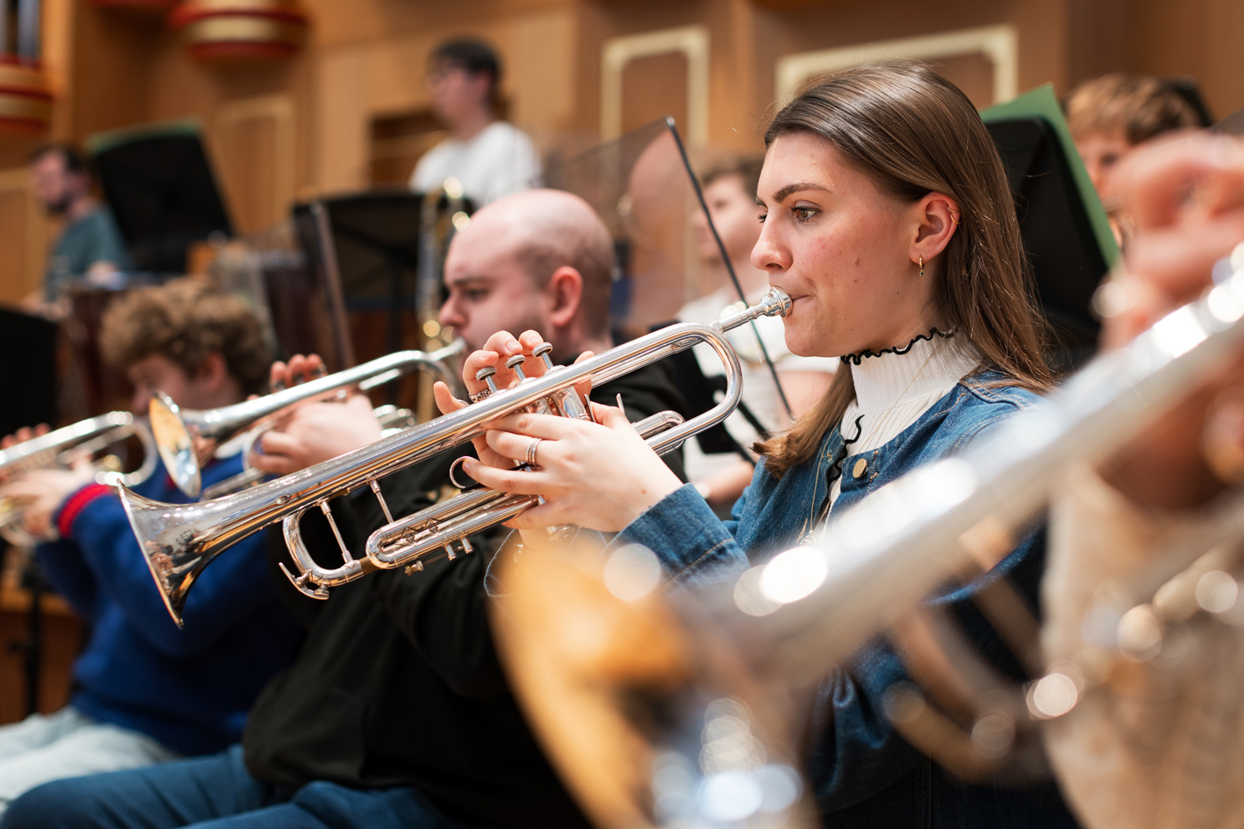 A group of trumpet players playing in a orchestra rehearsal.